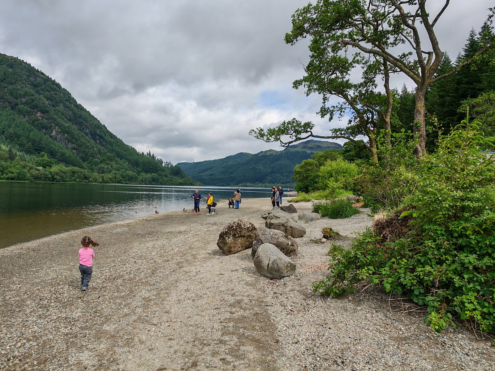 A young child exploring the shore of Loch Lubnaig on a family day tour